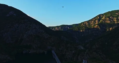 Large Dam Wall Road In Vast Mountain Range Vibrant Aerial Scene Sunset Rays Stock Footage 289415254