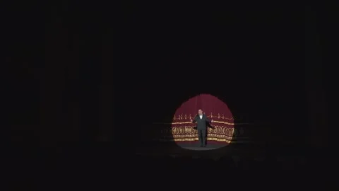 A large dark hall with a stage lit by a round soffit. A red curtain Vídeo Stock 263055098