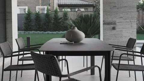 Large dark stoneware table and designer chairs in the courtyard Stock Footage 220773653