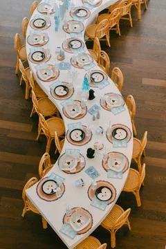 Large decorative dining table set up for a gathering with animal-themed plates Stock Photos