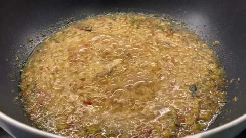 In a large, deep bowl, a rice dish is prepared, releasing bubbles when it boils. Stock Footage 150183894