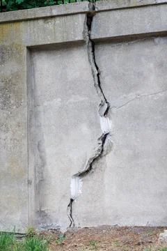 A large, deep crack in a high concrete fence. Repairing a deep crack in a c.. Stock Photos