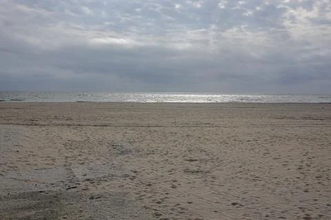 Large deserted sandy beach with flat ocean in the distance.  Stock Photos
