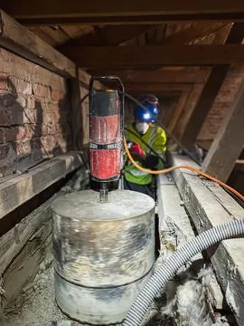 Large diameter concrete core drilling during attic construction work. Stockfoto's