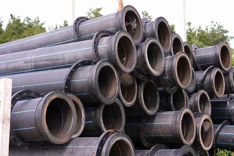 Large diameter construction pipes folded into a high pile outdoors Stock Photos