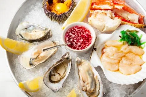 Large dish with fresh assorted seafood on ice - oysters, sea hedgehog, scallops Stock Photos