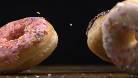 Large donuts falling into table surface in super slow-motion at black backg.. Stock Footage 273371065