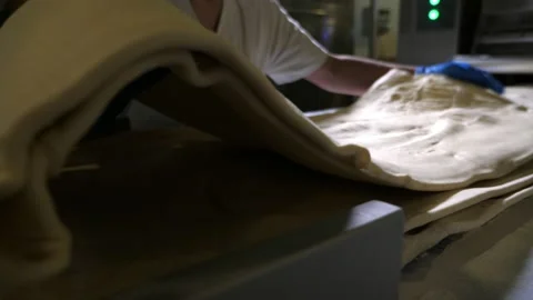 Large dough layer is placed on a pile of sheetsby a worker in a bakery plant Vídeo Stock 153262568