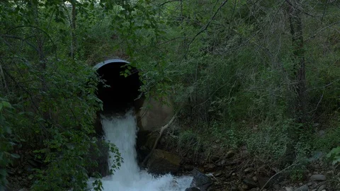 A large drain pipe discharging water into a stream Vidéo 111976359
