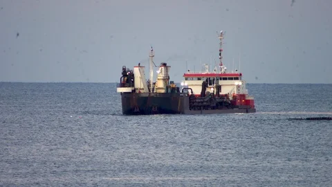 Large dredging ship connects with dredging pipe on ocean to pump sand on Stock Footage 119997484