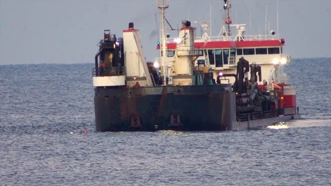 Large dredging ship connects with dredging pipe on ocean to pump sand on Stock Footage 119997976