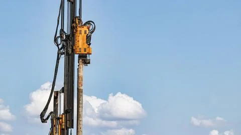 A large drilling machine reaches high into the sky as it operates on a cons.. Stock Photos