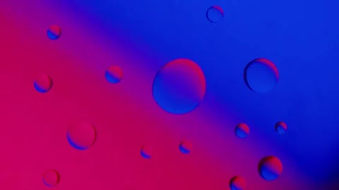 A large drop connects with a smaller drop on a blue-red gradient background. Vídeo Stock 303058701