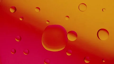A large drop connects to a smaller drop on a red-yellow gradient background. Vídeo Stock 303059092