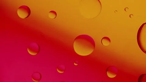 A large drop connects with two others on a red-yellow gradient background. 스톡 동영상 303059307
