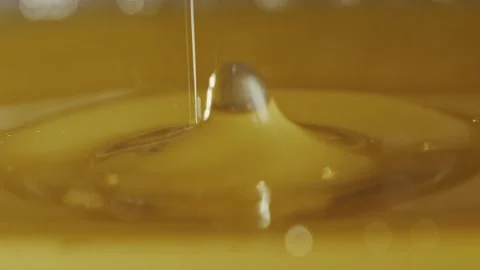 Large drop of viscous golden liquid dripped in slow motion and let loose a wave Stock Footage 309951975