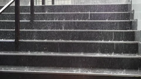 Large drops of heavy rain fall on the steps of a street staircase during the day Stock Footage 240769953