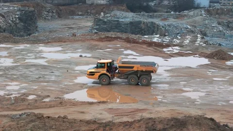 Large dump trucks transport stone to the crusher in a quarry while an excav.. Video stock 295953779