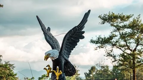 A large eagle statue with its wings spread out and a chain attached to its feet Stock Photos