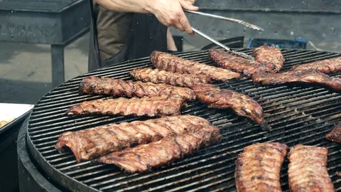 Large electric rotating grill for cooking ribs. Close up of the cook's hand t Stock Footage 129334857