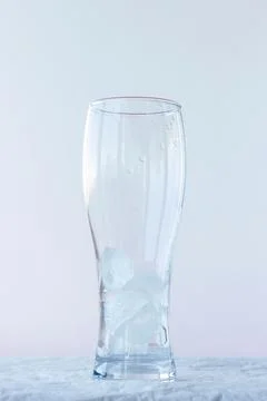 A large empty beer glass with ice stands on a white background Foto stock
