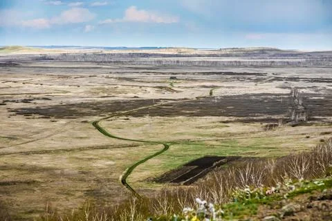 A large, empty field with a dirt road running through it Stock Photos