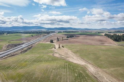 A large, empty field with a highway in the background Stock Photos