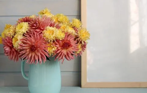 Large empty frame and a bouquet of dahlias and chrysanthemums in a blue jug on Stock-Fotos
