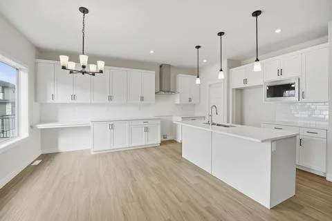 Large, empty kitchen with white cabinets and a white countertop Stock Photos