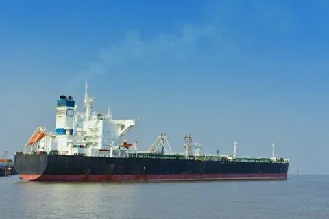 Large empty Merchant ship standing under a blue sky. Stock Photos