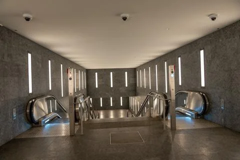 A large, empty, modern-looking subway station with escalators and stairs Stock Photos