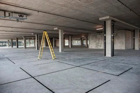 Large empty raw office space with a ladder set up on the floor. 스톡 사진