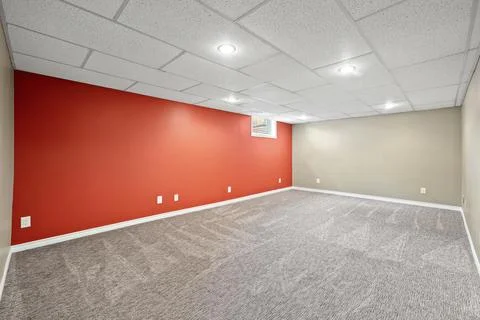 Large, empty room with a red wall and white trim Stock Photos