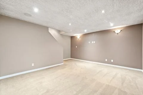 Large, empty room with a tan wall and a white carpet Stock Photos