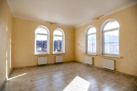 A large empty room with three windows and a white wall Stock Photos