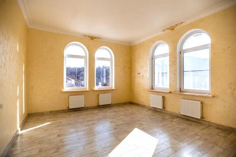A large empty room with three windows and a white wall Stock Photos