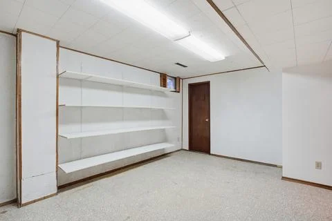 Large empty room with a white door and shelves Stock Photos