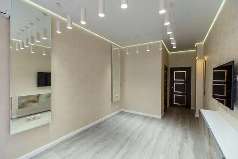 A large, empty room with a white wall and wooden floors Stock Photos