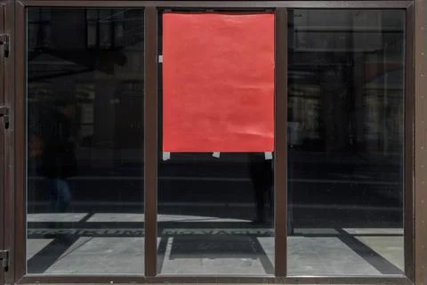 A large empty storefront with a red poster on the glass. Shop for rent. Stock Photos