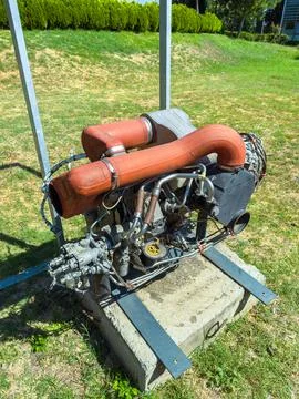 A large engine is placed on a concrete base in a green park area. The engine  Foto stock