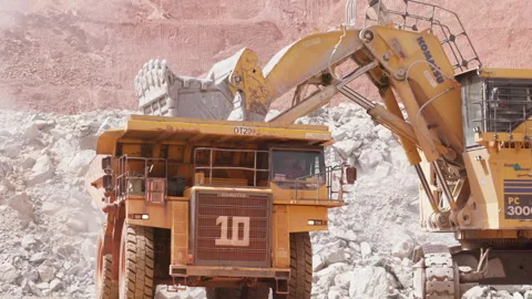 Large excavator depositing rubble onto the back of a heavy duty dump truck Stock Footage 241213799
