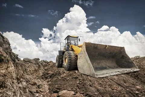 A large excavator digs into the earth at a construction site. The machine's b Photos