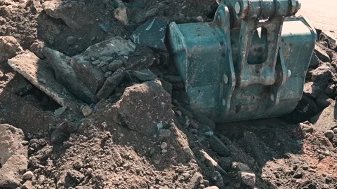 A large excavator digs into the ground at a construction site, removing dirt and Stock Footage 339016558