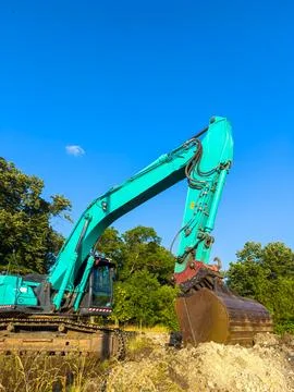 A large excavator digs into the ground at a construction site. The machine mo Stock Photos