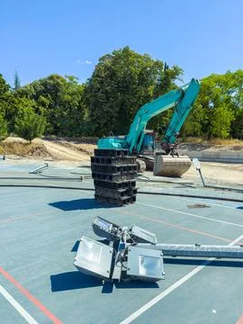 A large excavator is stacking black plastic blocks at a construction site in  Foto stock