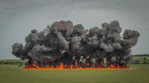 A large explosion during daylight in a field Stock Photos