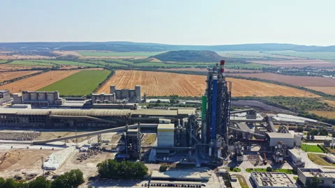 Large factory and surrounding fields with hills in the background during bright Stock Footage 341388935