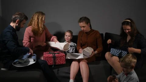 Large family happily wrapping multiple gifts in colorful paper Видео 340065808