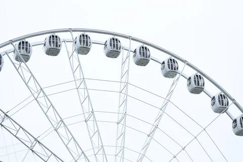 A large ferris wheel with a clock at the top, perfect for fairground or Stock Photos