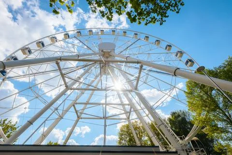 Large Ferris wheel structure with blue sky and fluffy clouds, sunlight shin.. Stock-Fotos